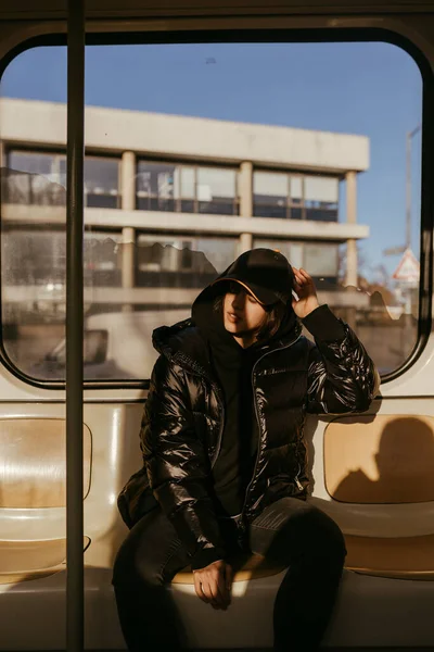 Молода жінка сидить на фоні вікна в громадському транспорті — стокове фото