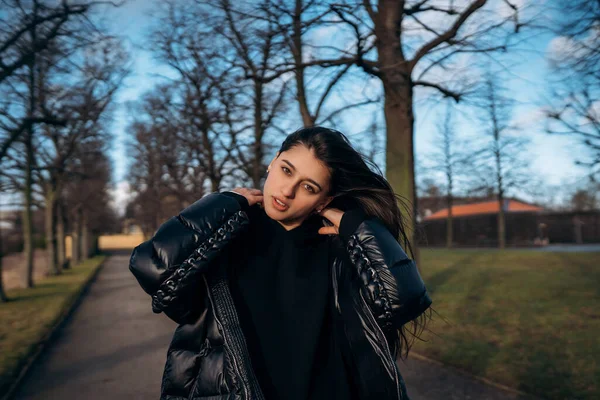 Retrato de uma menina morena se divertindo em um parque nos raios do sol brilhante. — Fotografia de Stock