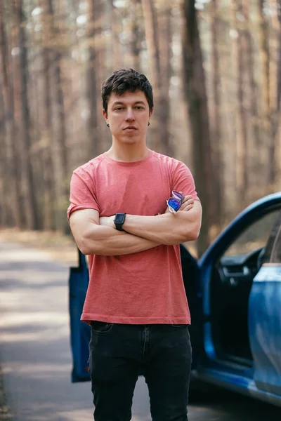 Beau homme debout sur la route près de la porte ouverte de sa voiture. — Photo