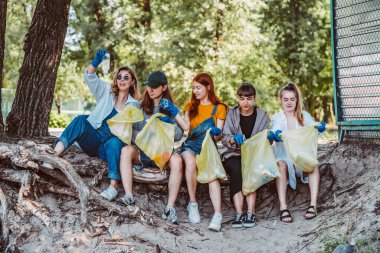 Bir grup aktivist arkadaş parkta plastik atık topluyor. Çevresel koruma.