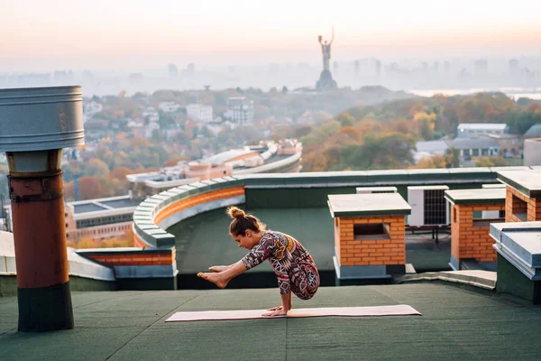 Mujer haciendo yoga en el techo de un rascacielos en la gran ciudad . —  Fotos de Stock