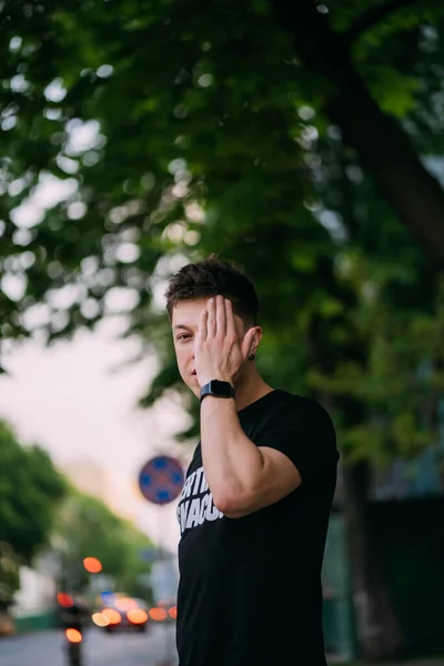 Ung vuxen man i svart t-shirt och jeans går på en stadsgata — Stockfoto