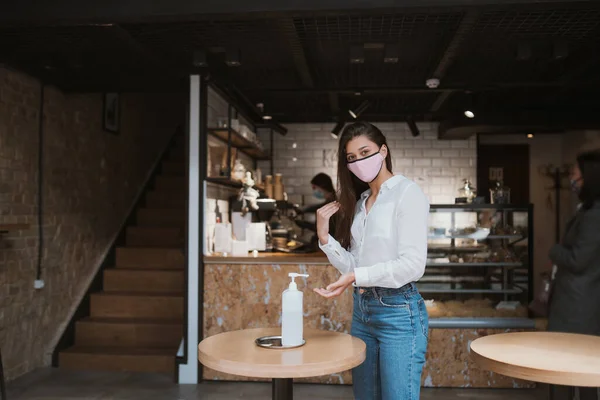 카페테리아에서 세정제 젤을 사용하는 여성이 코로나 바이러스의 손을 깨끗이 청소 한다. — 스톡 사진