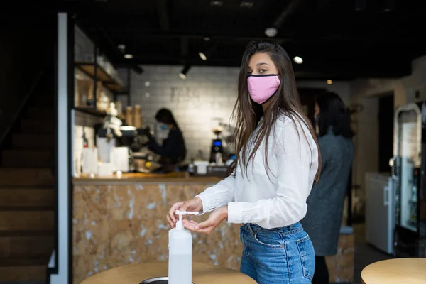 Woman using sanitizer gel cleans hands of coronavirus virus at cafe.