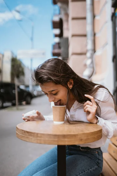 Hermosa joven en café de la calle bebe café — Foto de Stock