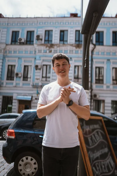 Мужчина в серой футболке и джинсах на фоне городской улицы — стоковое фото