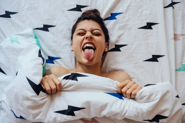 Close-up van mooie jonge vrouw ligt in bed bedekt met deken. — Stockfoto