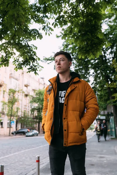 Ung vuxen man i gul jacka och jeans går på en stadsgata — Stockfoto