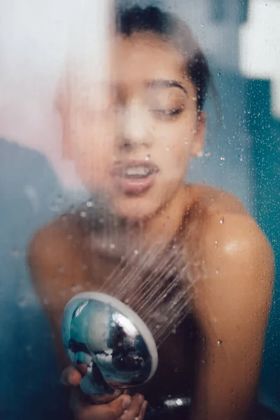 Belle femme derrière le verre avec des gouttes d'eau. — Photo