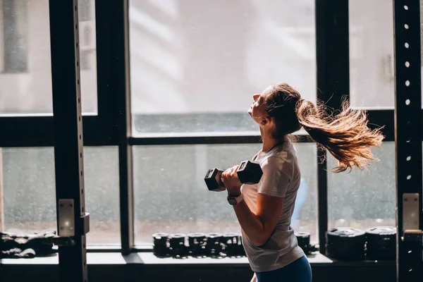 Štíhlý atletický dívka provádí fyzické cvičení s činky. — Stock fotografie