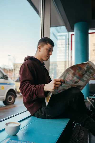 Portrait of man sitting at a cafe, reading newspapers and drinking coffee — Stock Photo, Image