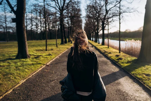 Porträtt av en brunett flicka som har roligt i en park i solens strålar. — Stockfoto