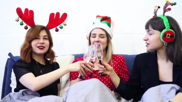 Sorrindo modelos femininos segurando copos de vinho e desfrutando de festa de pijama . — Vídeo de Stock
