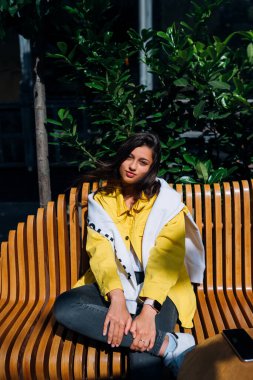 Esmer kız eski şehrin merkezinde bankta oturuyor..