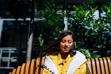 Esmer kız eski şehrin merkezinde bankta oturuyor..