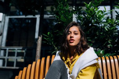 Esmer kız eski şehrin merkezinde bankta oturuyor..