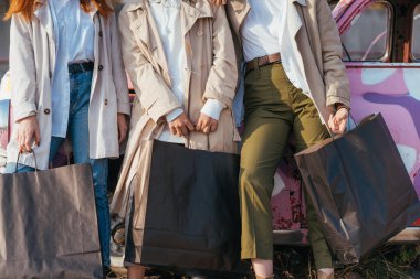 Genç kadınlar eski bir arabanın yanında poz veriyorlar.