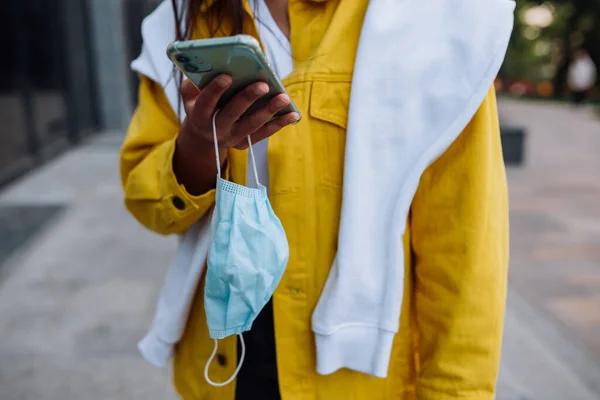 Menina segurando um smartphone e uma máscara — Fotografia de Stock