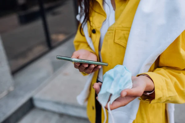 Akıllı telefon ve maske tutan bir kız. — Stok fotoğraf