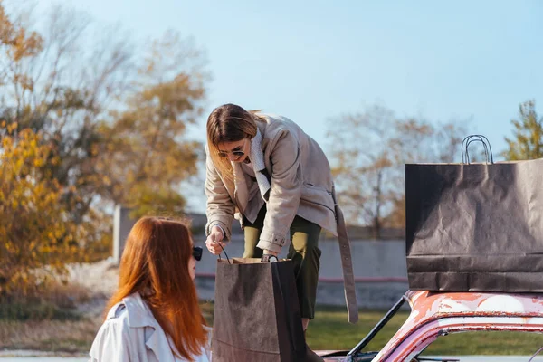 Mujeres jóvenes posando cerca de un viejo coche decorado — Foto de Stock