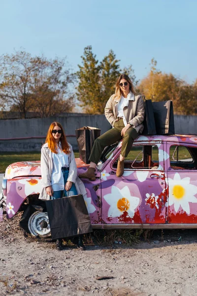 Mujeres jóvenes posando cerca de un viejo coche decorado — Foto de Stock