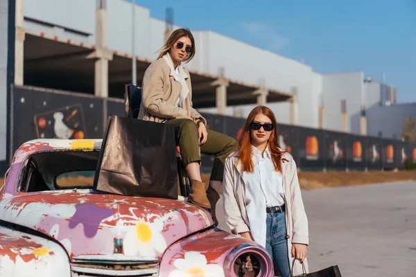 Молодые женщины позируют возле старой украшенной машины — стоковое фото