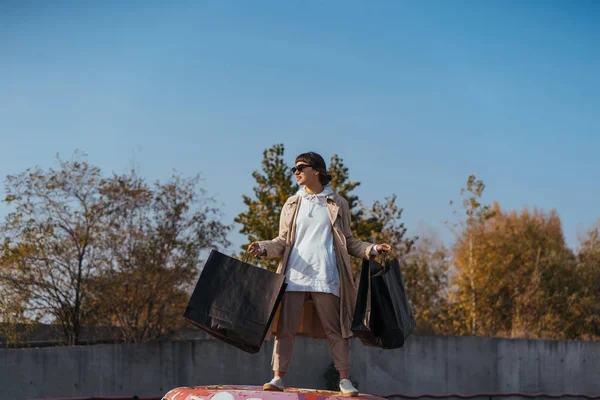 Egy fiatal nő áll egy kocsiban, táskákkal a kezében. — Stock Fotó