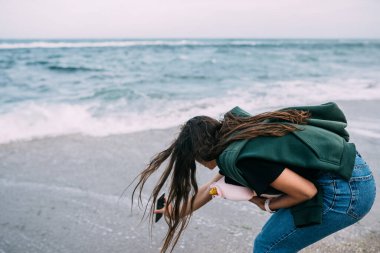 Kadın akıllı telefondan, deniz dalgalarından ateş eder.