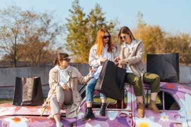 Süslü arabada poz veren genç kadınlar.