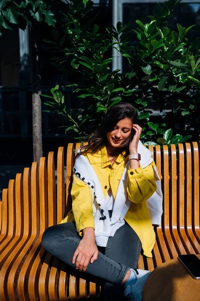 Esmer kız eski şehrin merkezinde bankta oturuyor..