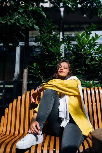 Esmer kız eski şehrin merkezinde bankta oturuyor..