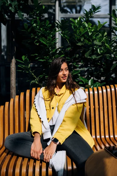 Morena menina sentada no banco na parte central da cidade velha . — Fotografia de Stock