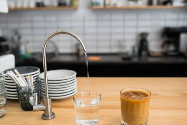 El agua se vierte de un grifo en un vaso —  Fotos de Stock