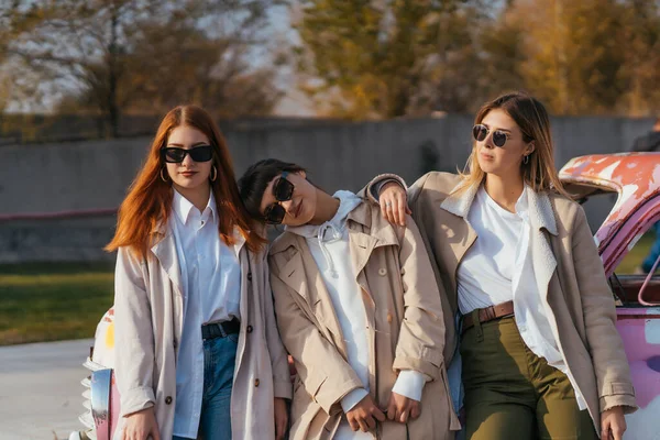 Mujeres jóvenes posando cerca de un viejo coche decorado — Foto de Stock