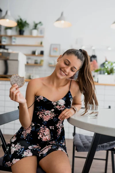 Glad leende flicka håller kakan i ett mysigt café. — Stockfoto