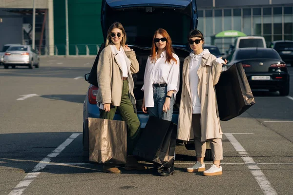 Les jeunes femmes à la voiture avec des sacs à provisions — Photo
