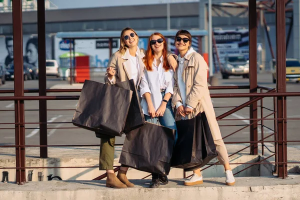 Mladé ženy s nákupními taškami na autobusové zastávce — Stock fotografie
