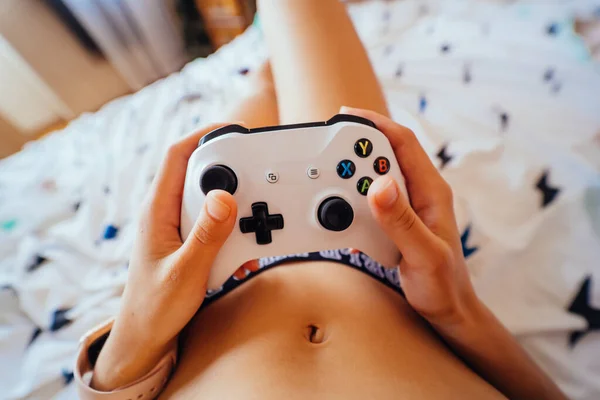 Ο τύπος που κάθεται στο κρεβάτι και παίζει βιντεοπαιχνίδι, κρατώντας χειριστήριο — Φωτογραφία Αρχείου