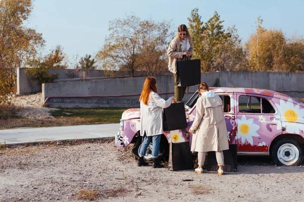 Jovens mulheres posando perto de um velho carro decorado — Fotografia de Stock