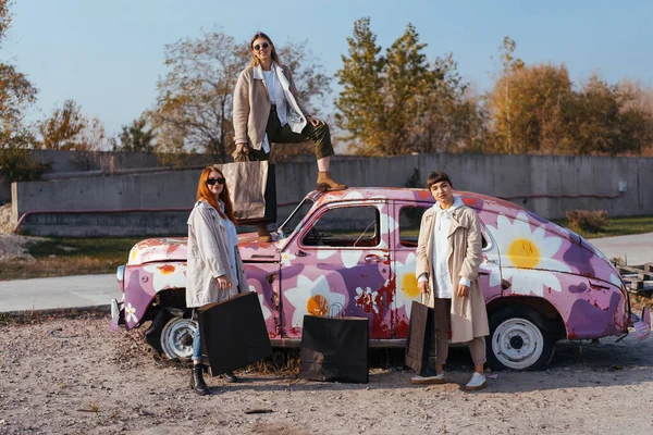 Jovens mulheres posando perto de um velho carro decorado — Fotografia de Stock