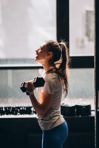 Chica atlética delgada realiza ejercicios físicos con mancuernas. —  Fotos de Stock