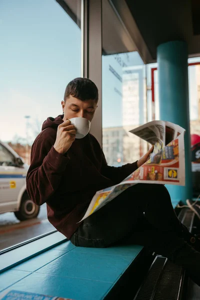 Портрет мужчины, сидящего в кафе, читающего газеты и пьющего кофе — стоковое фото