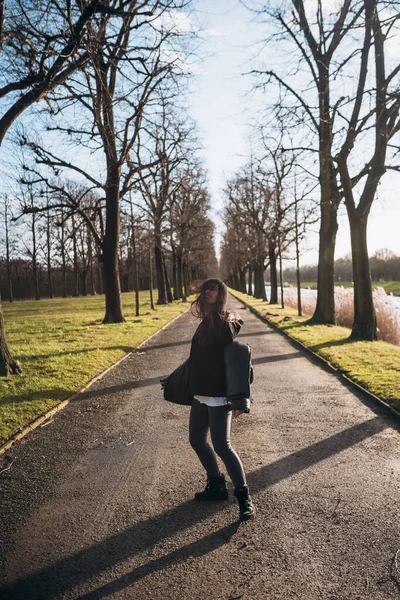 Portrait of a brunette girl having fun in a park in the rays of the bright sun. — Stock Photo, Image