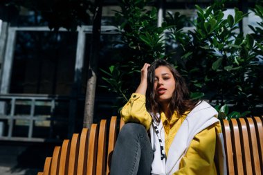 Esmer kız eski şehrin merkezinde bankta oturuyor..