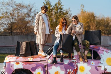 Süslü arabada poz veren genç kadınlar.