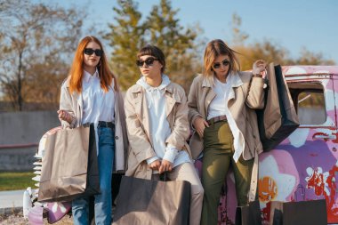 Genç kadınlar eski bir arabanın yanında poz veriyorlar.