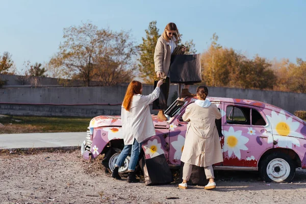 Jovens mulheres posando perto de um velho carro decorado — Fotografia de Stock