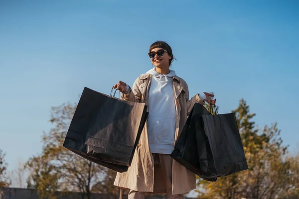 Mladá žena stojí v autě s taškami v rukou — Stock fotografie