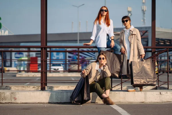 Mujeres jóvenes con bolsas de compras en una parada de autobús — Foto de Stock