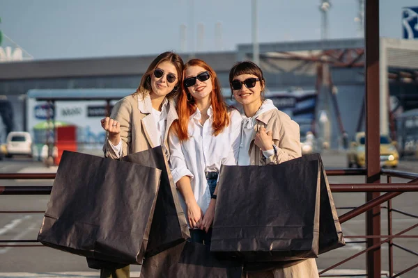 Mladé ženy s nákupními taškami na autobusové zastávce — Stock fotografie